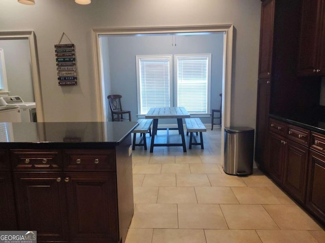 kitchen featuring washer and dryer, light tile patterned flooring, and dark brown cabinets