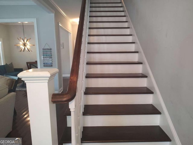 stairs featuring a notable chandelier and ornamental molding