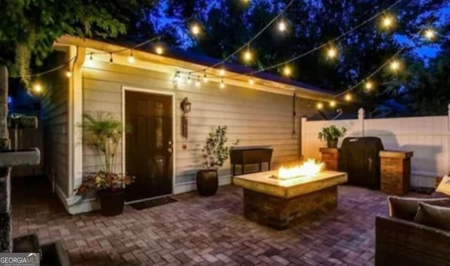 patio at twilight featuring area for grilling and an outdoor fire pit