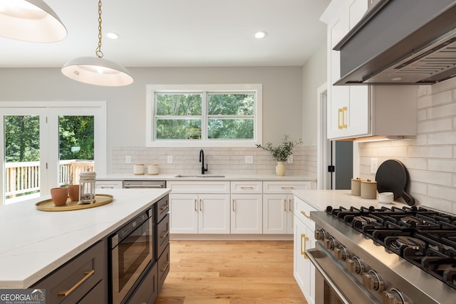 kitchen with high end stove, sink, white cabinets, built in microwave, and extractor fan