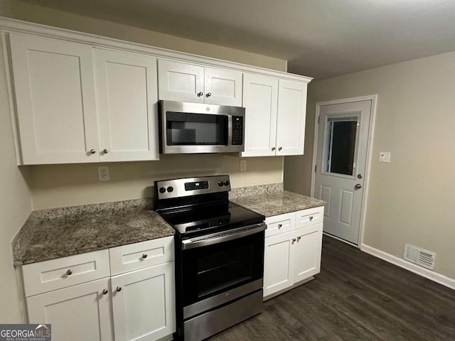 kitchen featuring dark stone counters, dark hardwood / wood-style floors, appliances with stainless steel finishes, and white cabinetry