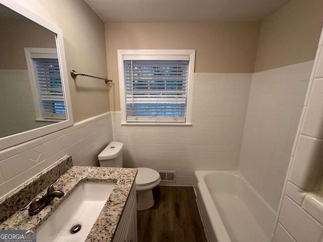 bathroom with toilet, tile walls, wood-type flooring, decorative backsplash, and vanity