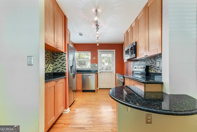 kitchen featuring decorative backsplash, appliances with stainless steel finishes, light hardwood / wood-style floors, and dark stone countertops