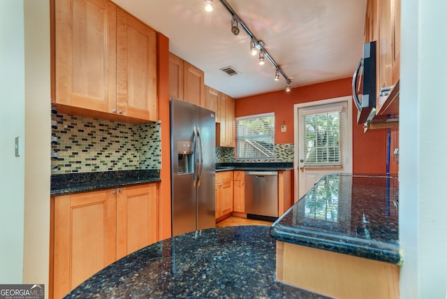 kitchen featuring appliances with stainless steel finishes, dark stone countertops, tasteful backsplash, and track lighting