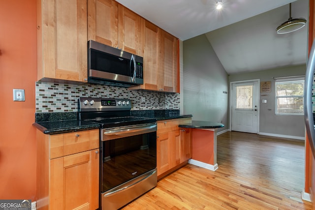 kitchen with light wood-type flooring, stainless steel appliances, lofted ceiling, decorative light fixtures, and dark stone countertops