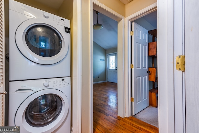 clothes washing area featuring stacked washer / drying machine and wood-type flooring