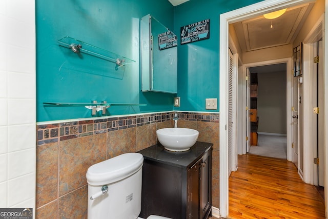 bathroom with toilet, vanity, wood-type flooring, and tile walls