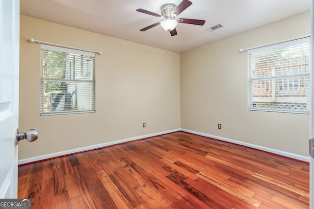 empty room featuring a wealth of natural light, hardwood / wood-style floors, and ceiling fan