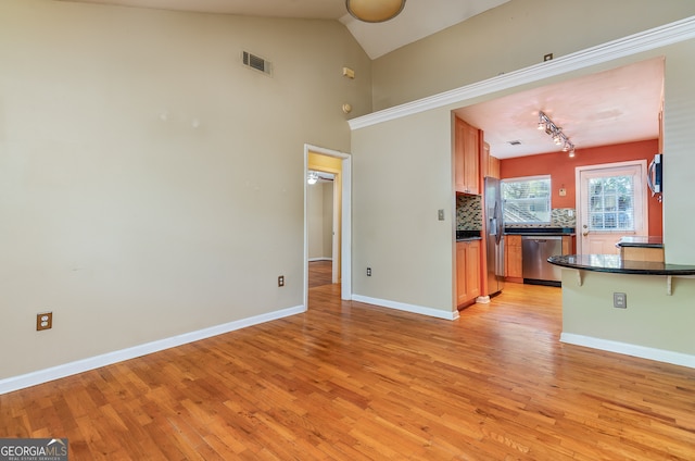 kitchen with tasteful backsplash, rail lighting, appliances with stainless steel finishes, high vaulted ceiling, and light hardwood / wood-style flooring