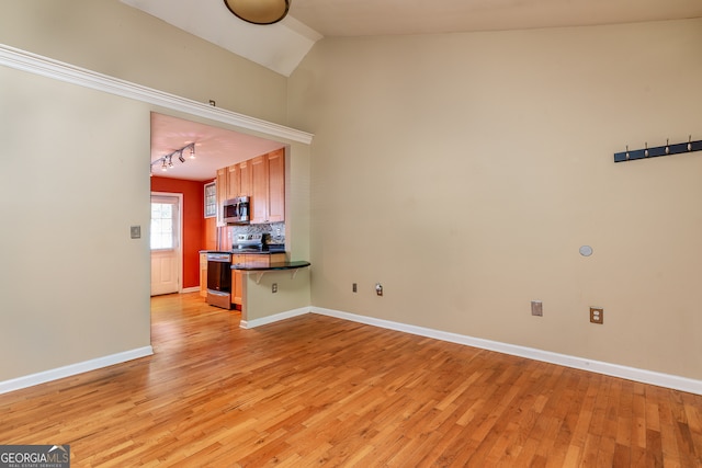 interior space with kitchen peninsula, tasteful backsplash, a breakfast bar area, appliances with stainless steel finishes, and light hardwood / wood-style floors