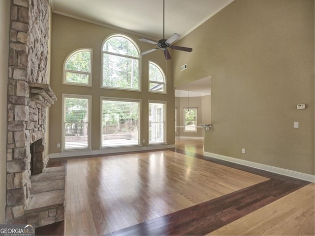 unfurnished living room with hardwood / wood-style flooring, a fireplace, ceiling fan, and high vaulted ceiling