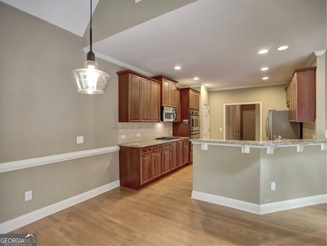 kitchen featuring light stone counters, light hardwood / wood-style floors, a kitchen bar, hanging light fixtures, and appliances with stainless steel finishes