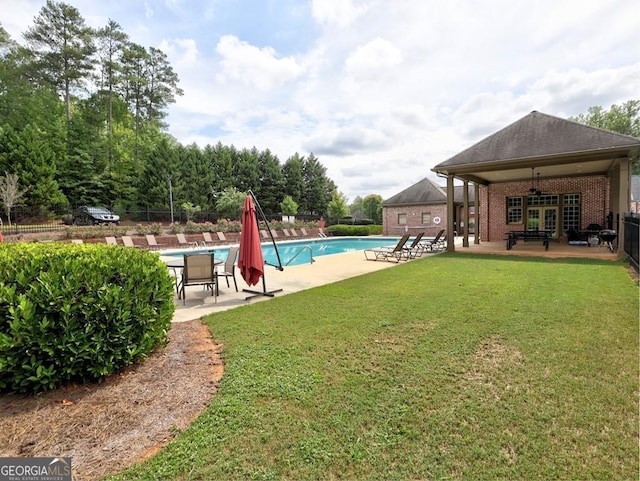 view of swimming pool with ceiling fan, a yard, and a patio area