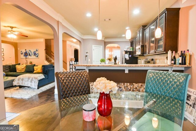 kitchen featuring backsplash, crown molding, dark hardwood / wood-style floors, ceiling fan, and pendant lighting