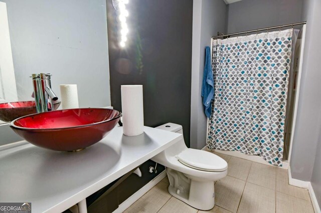 bathroom featuring toilet, walk in shower, sink, and tile patterned flooring