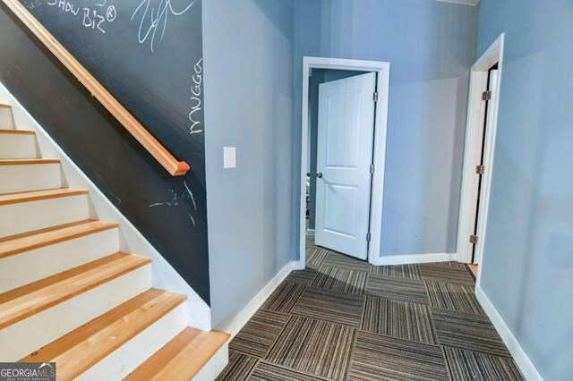 hall with dark colored carpet