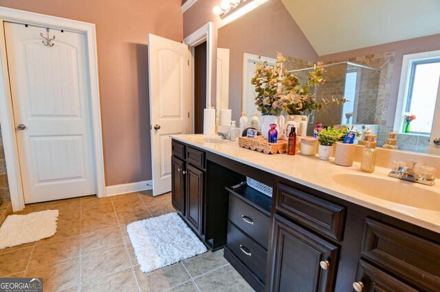 bathroom with lofted ceiling, vanity, tile patterned floors, and walk in shower