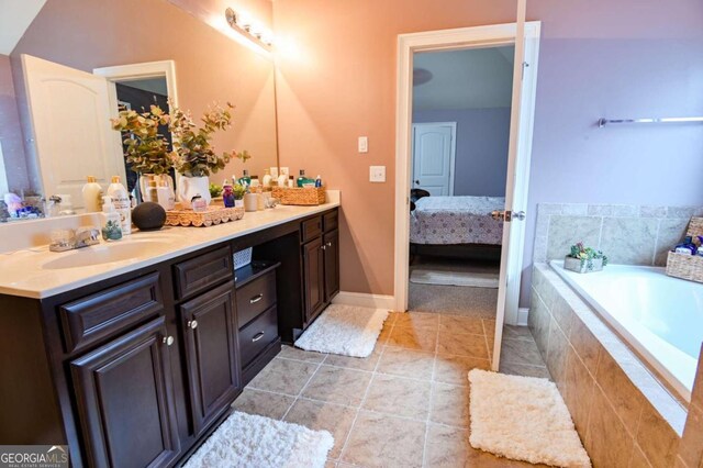 bathroom with vanity, a relaxing tiled tub, and tile patterned floors