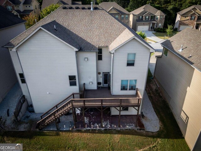 rear view of property with a yard, a wooden deck, and a patio