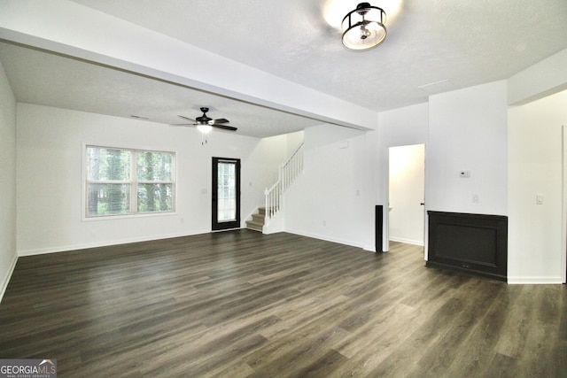 unfurnished living room with stairs, dark wood-style floors, and baseboards