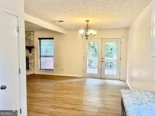 interior space featuring french doors, an inviting chandelier, a textured ceiling, and light hardwood / wood-style flooring