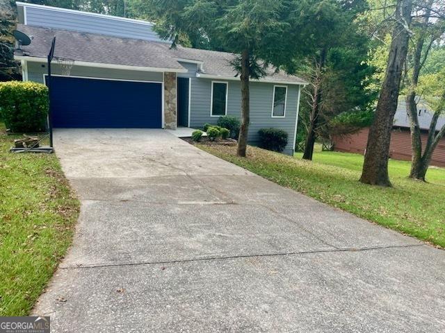 ranch-style home with a garage and a front lawn