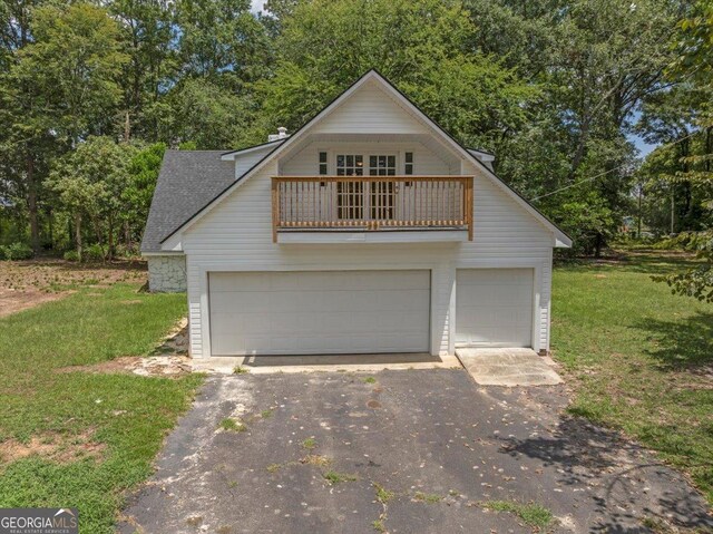 front of property with a balcony, a garage, and a front lawn