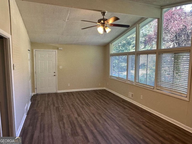 empty room with vaulted ceiling, dark hardwood / wood-style flooring, ceiling fan, and a textured ceiling