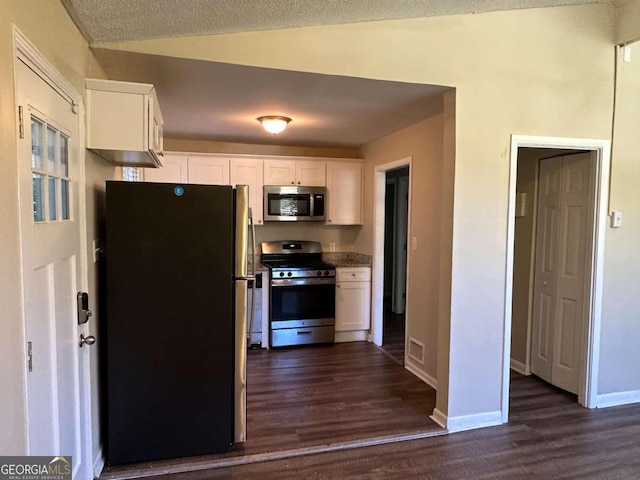 kitchen featuring appliances with stainless steel finishes, dark hardwood / wood-style flooring, white cabinetry, and a textured ceiling