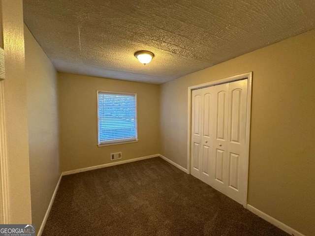 unfurnished bedroom featuring carpet, a textured ceiling, and a closet