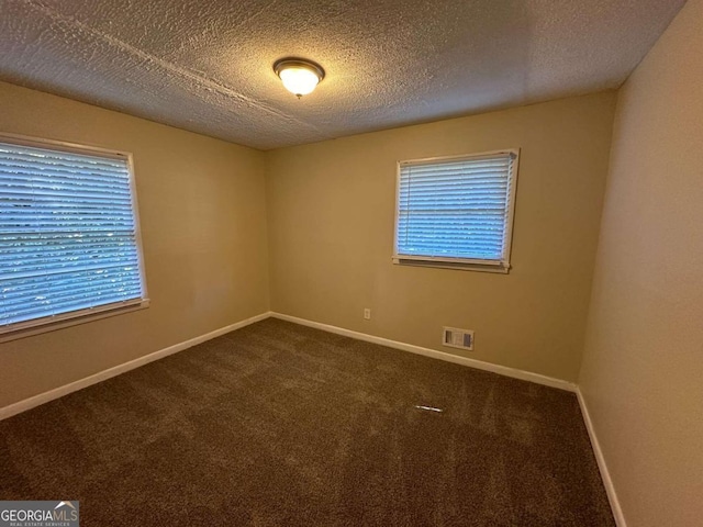 carpeted empty room with a textured ceiling