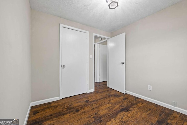 unfurnished bedroom with a textured ceiling and dark hardwood / wood-style floors