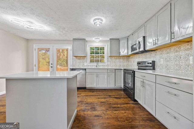 kitchen with a textured ceiling, tasteful backsplash, dark hardwood / wood-style floors, appliances with stainless steel finishes, and gray cabinetry