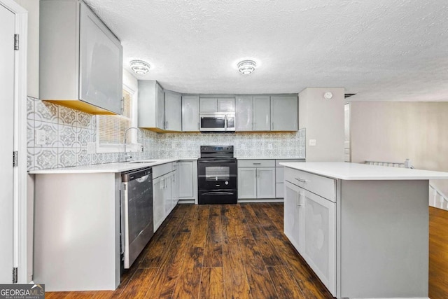 kitchen featuring stainless steel appliances, sink, gray cabinets, dark wood-type flooring, and a textured ceiling