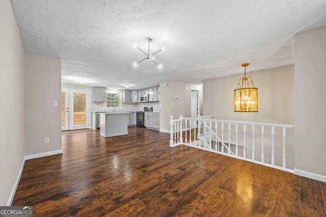 unfurnished living room featuring dark hardwood / wood-style floors, an inviting chandelier, and a textured ceiling