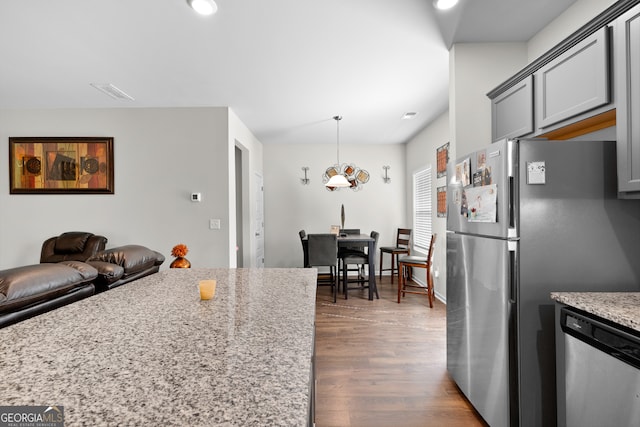 kitchen featuring light stone countertops, stainless steel appliances, dark hardwood / wood-style flooring, gray cabinets, and pendant lighting