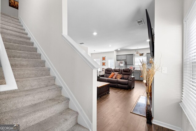 staircase with baseboards, hardwood / wood-style flooring, visible vents, and recessed lighting