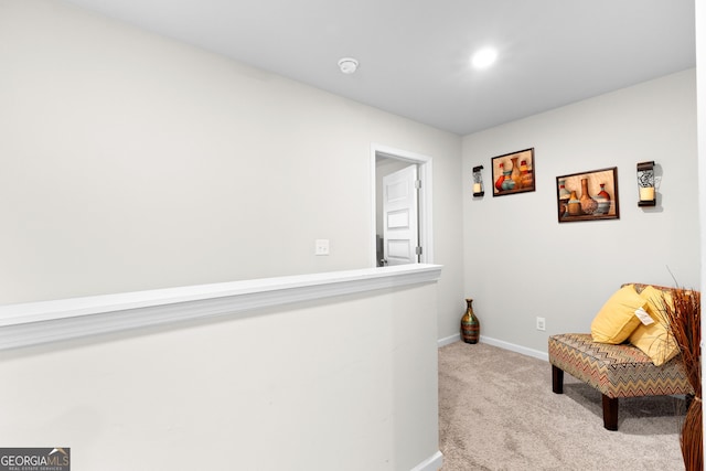 sitting room with baseboards and light carpet