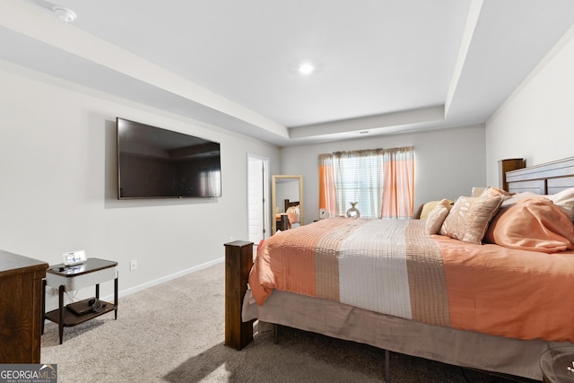 carpeted bedroom with baseboards and a raised ceiling