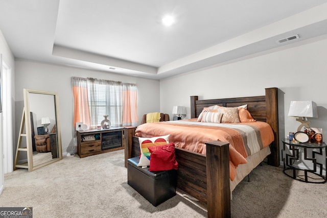 bedroom featuring a tray ceiling, visible vents, and carpet flooring