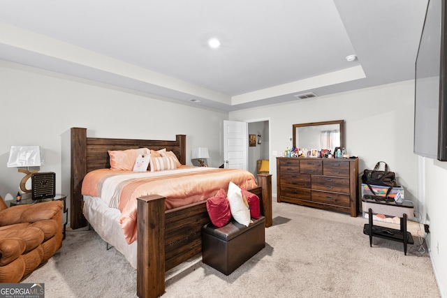 bedroom featuring a tray ceiling, visible vents, and light carpet