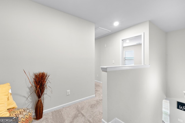 hallway with attic access, baseboards, and carpet