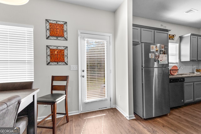 kitchen with light stone counters, dark wood-type flooring, stainless steel appliances, and gray cabinetry