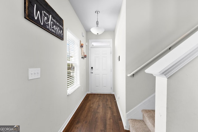entryway featuring wood finished floors, baseboards, and stairway