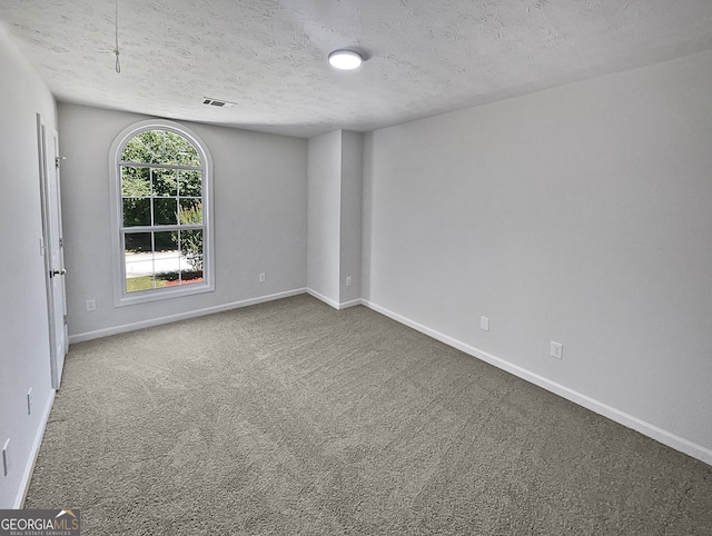 carpeted empty room featuring a textured ceiling