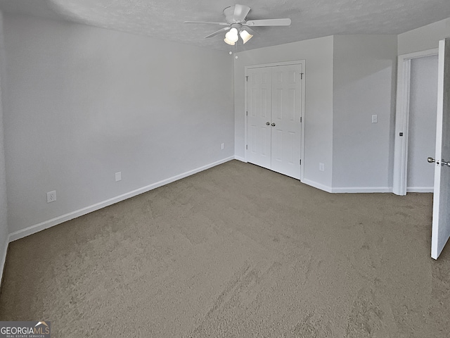 unfurnished bedroom featuring a closet, ceiling fan, carpet, and a textured ceiling