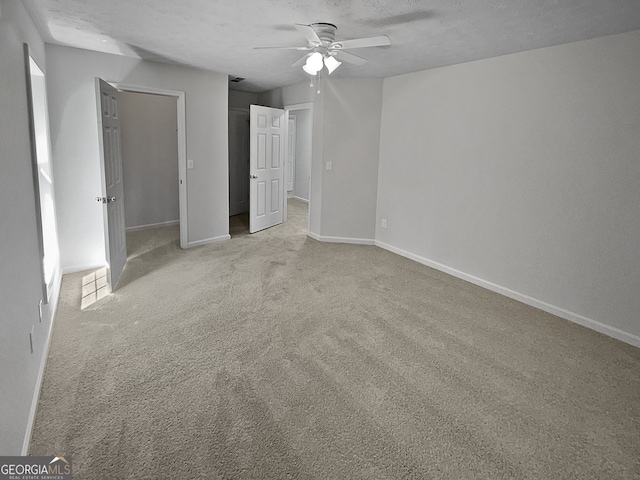 unfurnished room featuring ceiling fan, light colored carpet, and a textured ceiling