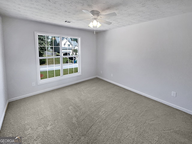 empty room featuring a textured ceiling, carpet, and ceiling fan