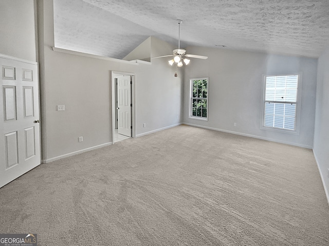 empty room featuring vaulted ceiling, a textured ceiling, plenty of natural light, and ceiling fan