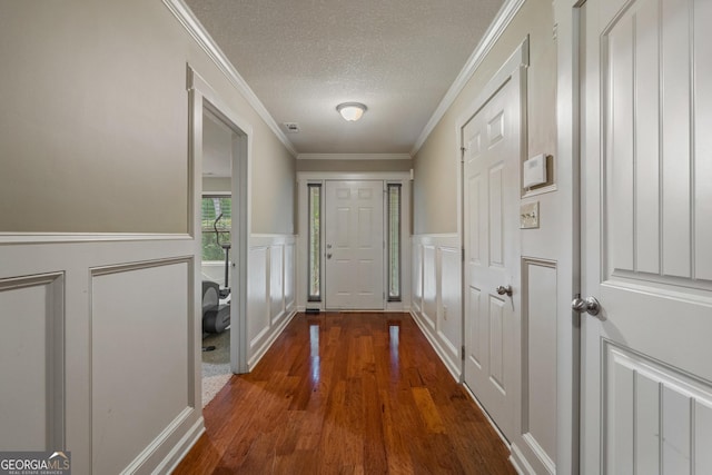 doorway with ornamental molding, a textured ceiling, and dark hardwood / wood-style flooring